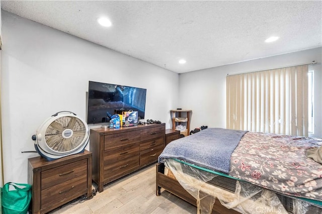 bedroom with light hardwood / wood-style floors, multiple windows, and a textured ceiling