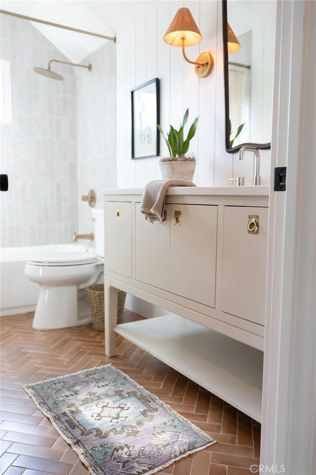 full bathroom with toilet, tiled shower / bath, and vanity