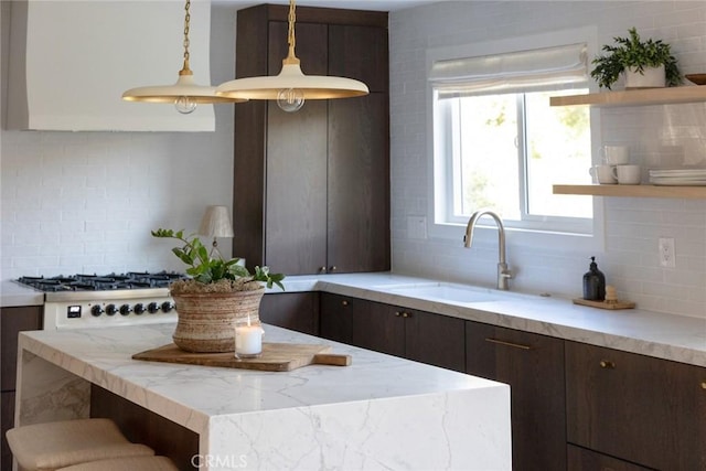 kitchen with pendant lighting, sink, backsplash, stainless steel gas cooktop, and dark brown cabinets