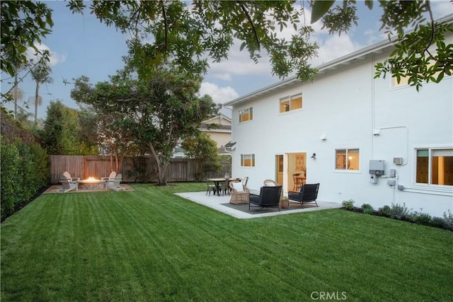 rear view of property with an outdoor fire pit, a lawn, and a patio