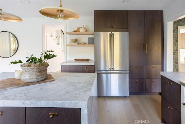 kitchen with dark brown cabinets, light hardwood / wood-style flooring, hanging light fixtures, and high end fridge