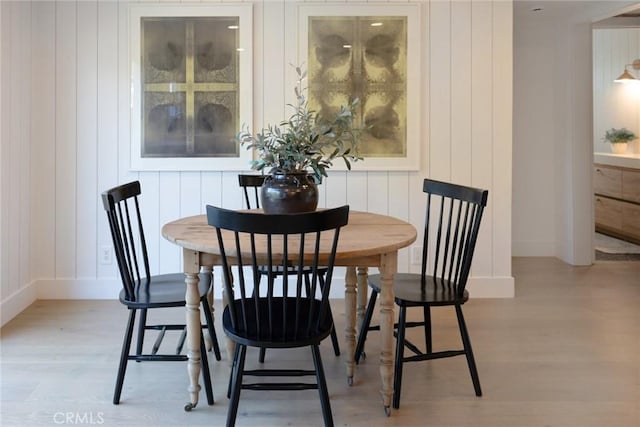 dining room with light hardwood / wood-style floors and wood walls