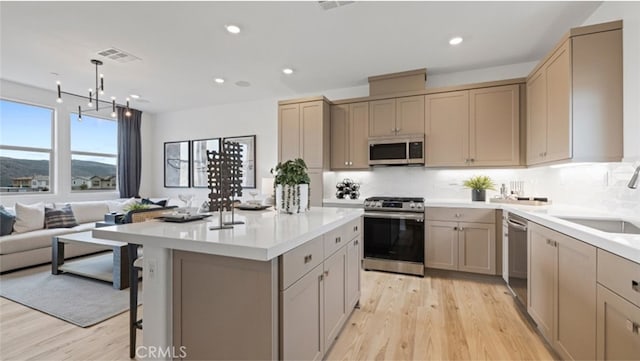 kitchen with sink, backsplash, appliances with stainless steel finishes, and light wood-type flooring