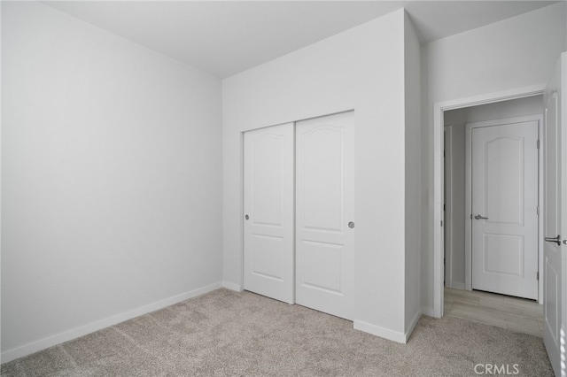 unfurnished bedroom with light carpet and a closet