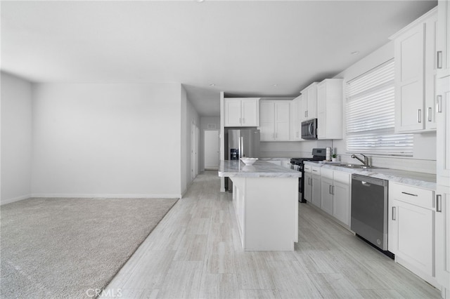 kitchen featuring a kitchen island, a kitchen bar, sink, stainless steel appliances, and white cabinets