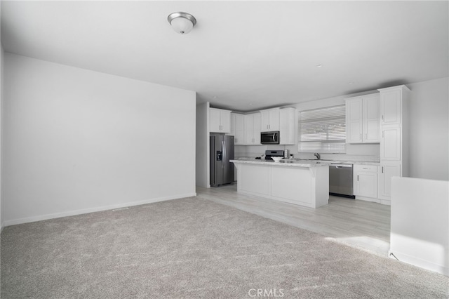 kitchen featuring light colored carpet, appliances with stainless steel finishes, white cabinetry, and a kitchen island