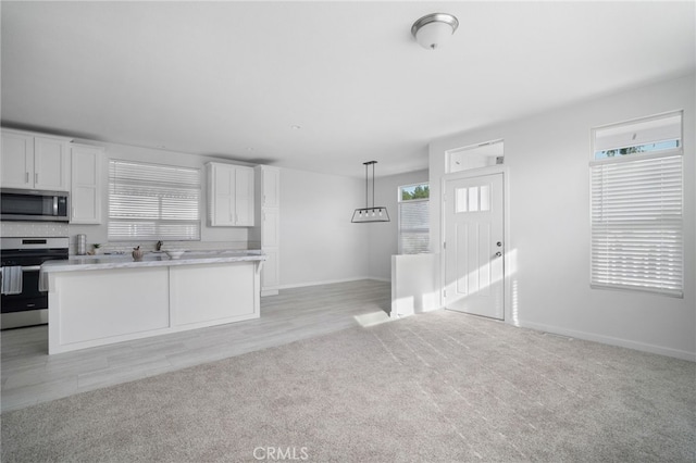 kitchen with plenty of natural light, stainless steel appliances, white cabinets, and hanging light fixtures