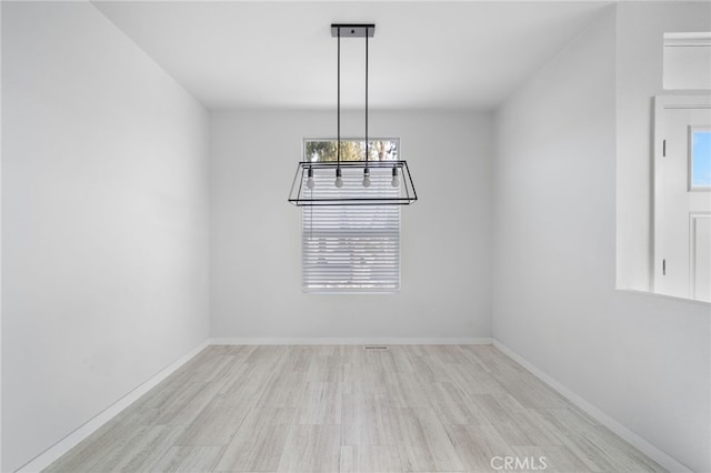 unfurnished dining area with light wood-type flooring and an inviting chandelier