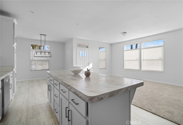 kitchen with gray cabinetry, dishwasher, hanging light fixtures, light hardwood / wood-style flooring, and a center island