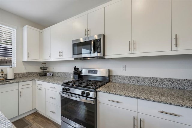 kitchen featuring appliances with stainless steel finishes, light stone counters, and white cabinetry