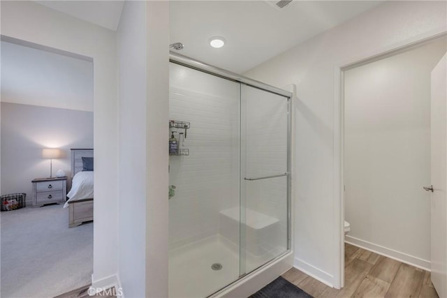 bathroom with toilet, an enclosed shower, and hardwood / wood-style flooring