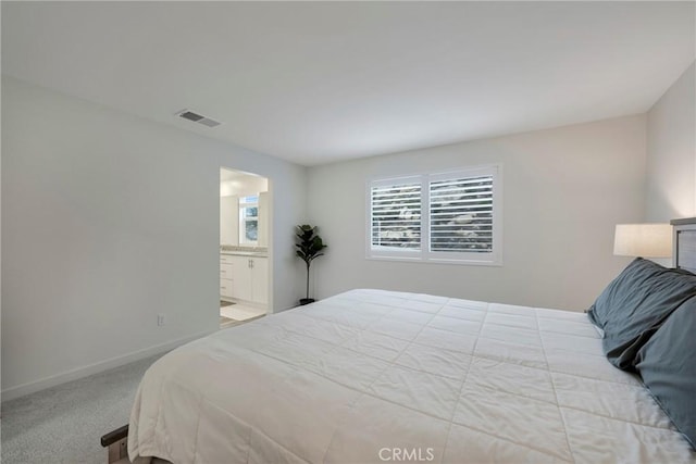 bedroom with ensuite bathroom and light carpet