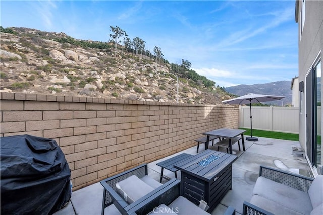 view of patio / terrace with area for grilling, a mountain view, and a fire pit