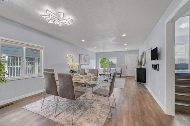 dining space with a textured ceiling and light hardwood / wood-style flooring