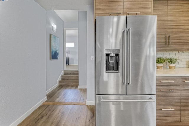 kitchen featuring hardwood / wood-style flooring, backsplash, and stainless steel fridge