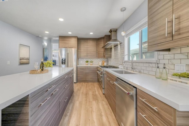 kitchen featuring pendant lighting, decorative backsplash, sink, appliances with stainless steel finishes, and wall chimney exhaust hood