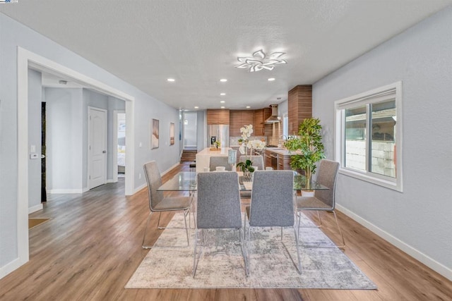 unfurnished dining area featuring a textured ceiling and light hardwood / wood-style floors