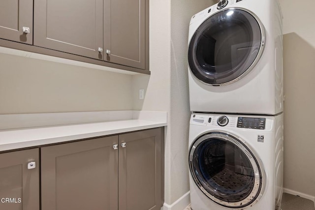 laundry area featuring stacked washing maching and dryer and cabinets