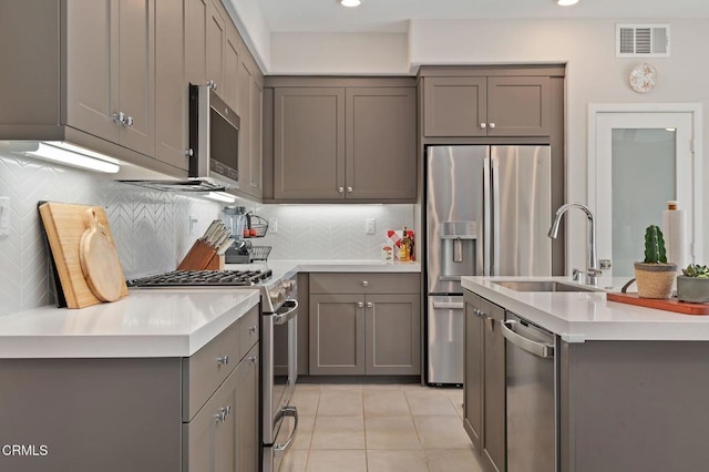 kitchen featuring a kitchen island with sink, backsplash, and appliances with stainless steel finishes