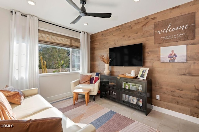 living room with ceiling fan, light tile patterned floors, and wooden walls