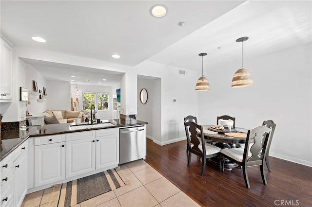 kitchen with light tile patterned floors, white cabinetry, decorative light fixtures, dishwasher, and sink