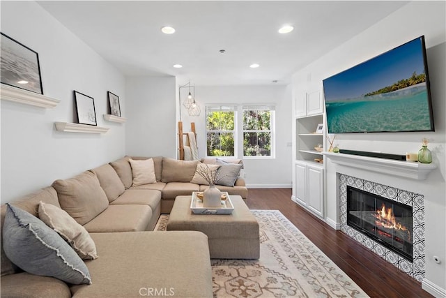 living room with dark wood-type flooring and a tiled fireplace