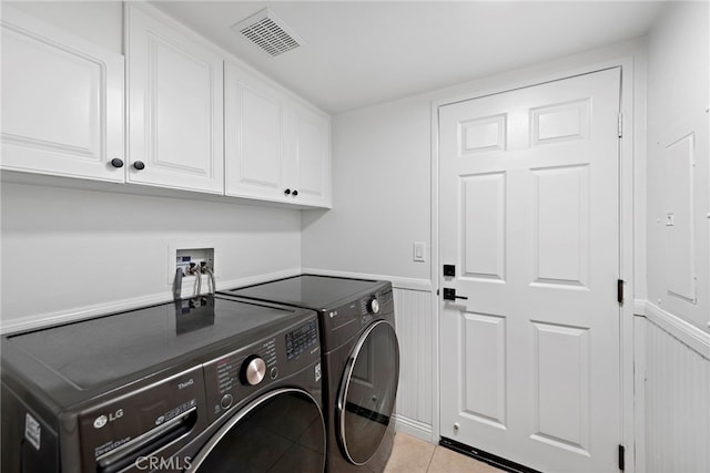 laundry room featuring cabinets, light tile patterned flooring, and separate washer and dryer