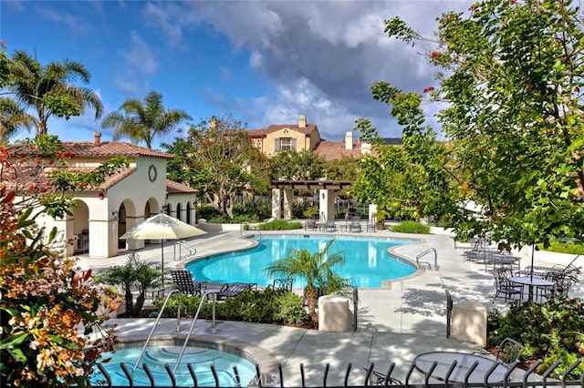 view of swimming pool featuring a community hot tub and a patio area