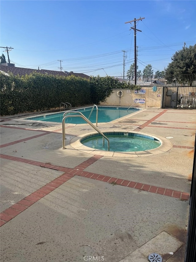 view of swimming pool featuring a hot tub and a patio