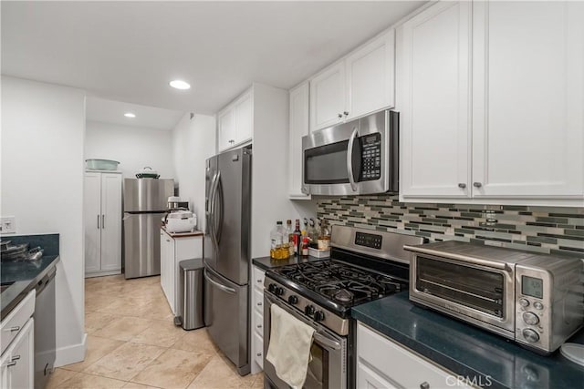 kitchen with decorative backsplash, stainless steel appliances, white cabinets, and light tile patterned flooring