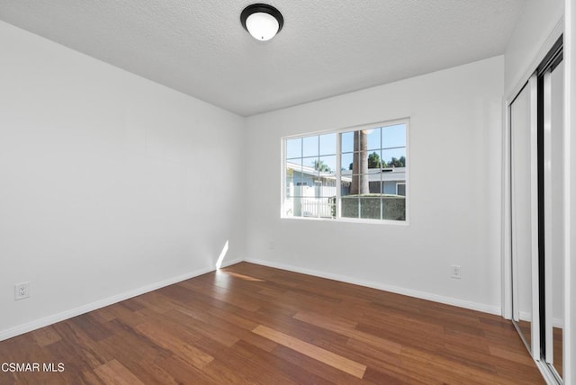 unfurnished bedroom with hardwood / wood-style flooring, a textured ceiling, and a closet