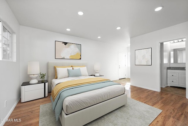 bedroom with ensuite bath and hardwood / wood-style floors