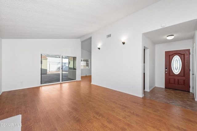 entrance foyer featuring vaulted ceiling, a textured ceiling, and hardwood / wood-style flooring