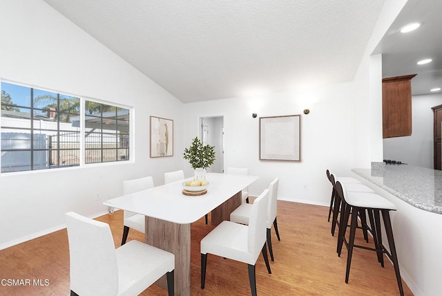 dining room with vaulted ceiling and light wood-type flooring