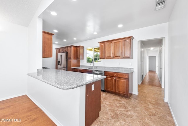 kitchen featuring light stone countertops, sink, kitchen peninsula, and stainless steel appliances