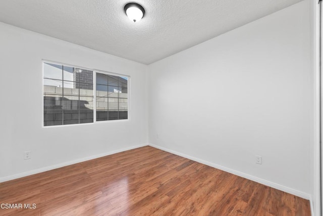 spare room with a textured ceiling and wood-type flooring