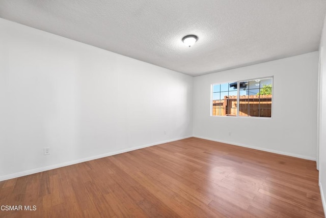 spare room with a textured ceiling and hardwood / wood-style flooring