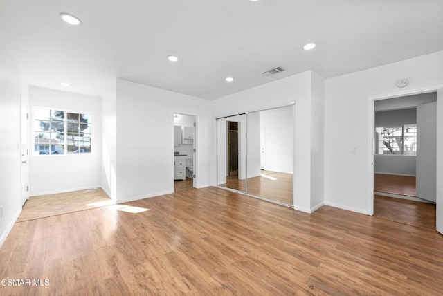 interior space featuring light wood-type flooring, ensuite bath, and multiple windows