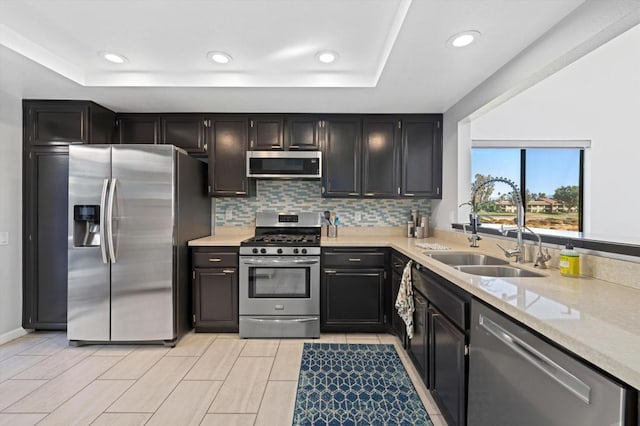 kitchen featuring stainless steel appliances, tasteful backsplash, sink, and a tray ceiling