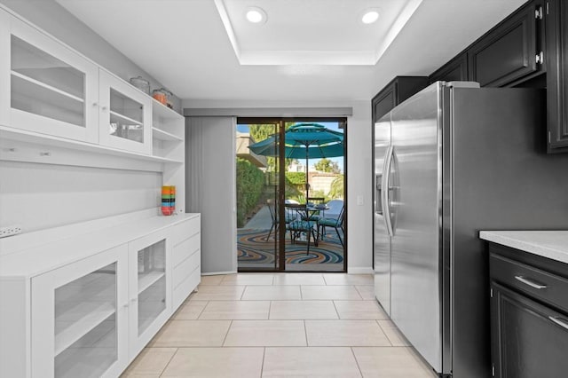 kitchen featuring a raised ceiling, light tile patterned floors, and stainless steel fridge