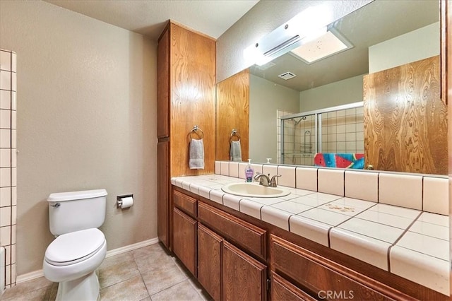 bathroom with tile patterned floors, toilet, vanity, and walk in shower