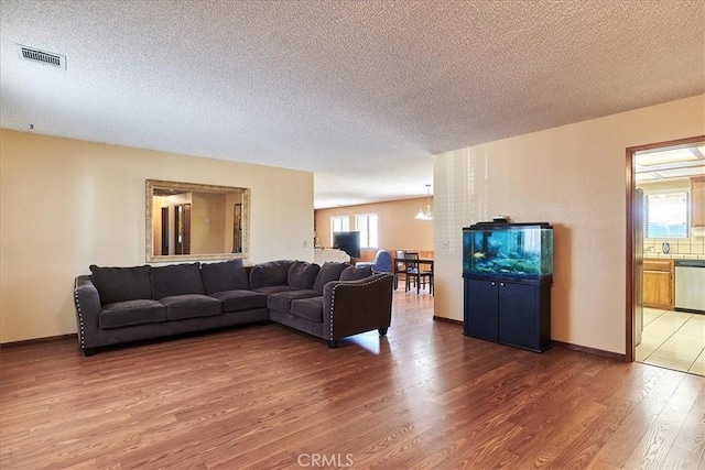 living room with hardwood / wood-style flooring, a textured ceiling, and a notable chandelier