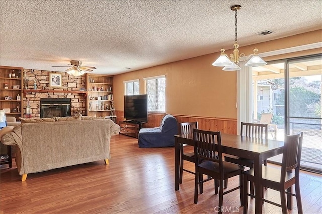 dining space with hardwood / wood-style flooring, built in features, wooden walls, and a fireplace