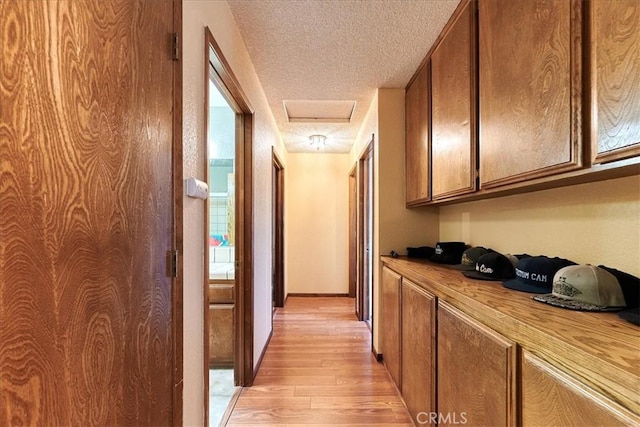 corridor with light hardwood / wood-style floors and a textured ceiling