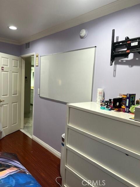 bedroom featuring dark wood-type flooring and crown molding