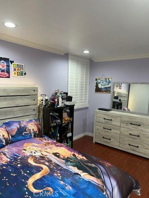 bedroom with dark wood-type flooring and crown molding