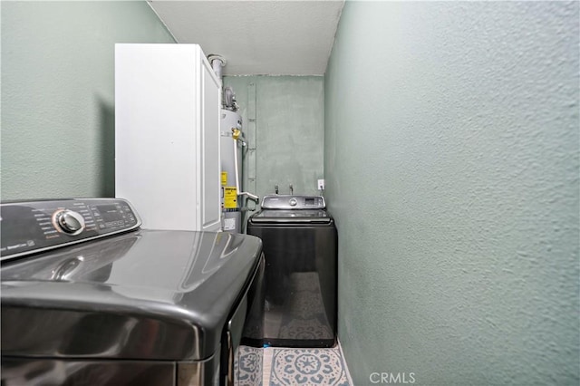 laundry room featuring strapped water heater and washing machine and clothes dryer