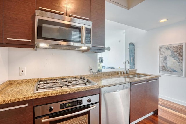 kitchen with light stone countertops, dark hardwood / wood-style floors, sink, and stainless steel appliances