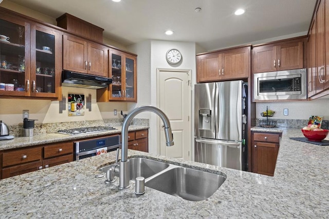 kitchen with sink, stainless steel appliances, and light stone countertops