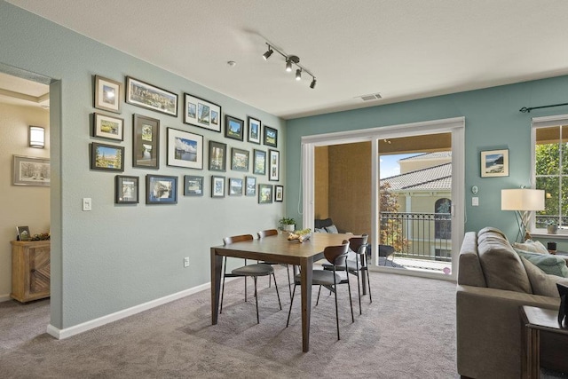 carpeted dining area with track lighting